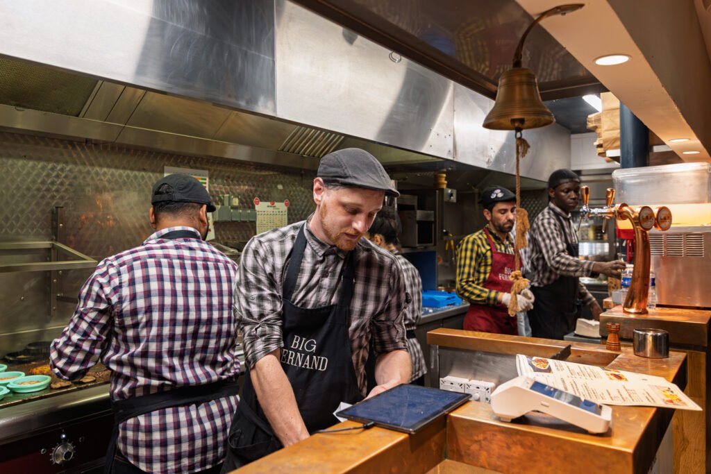 Cuisiniers en tabliers dans la cuisine du restaurant de burgers Big Fernand à Paris.
