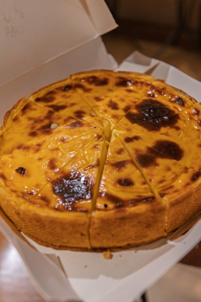 Flan pâtissier entier coupé en parts, présenté dans sa boîte en carton à emporter.