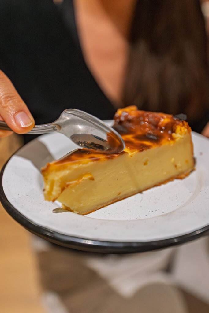 Une part de flan pâtissier servie dans une assiette, dégustée à la cuillère.