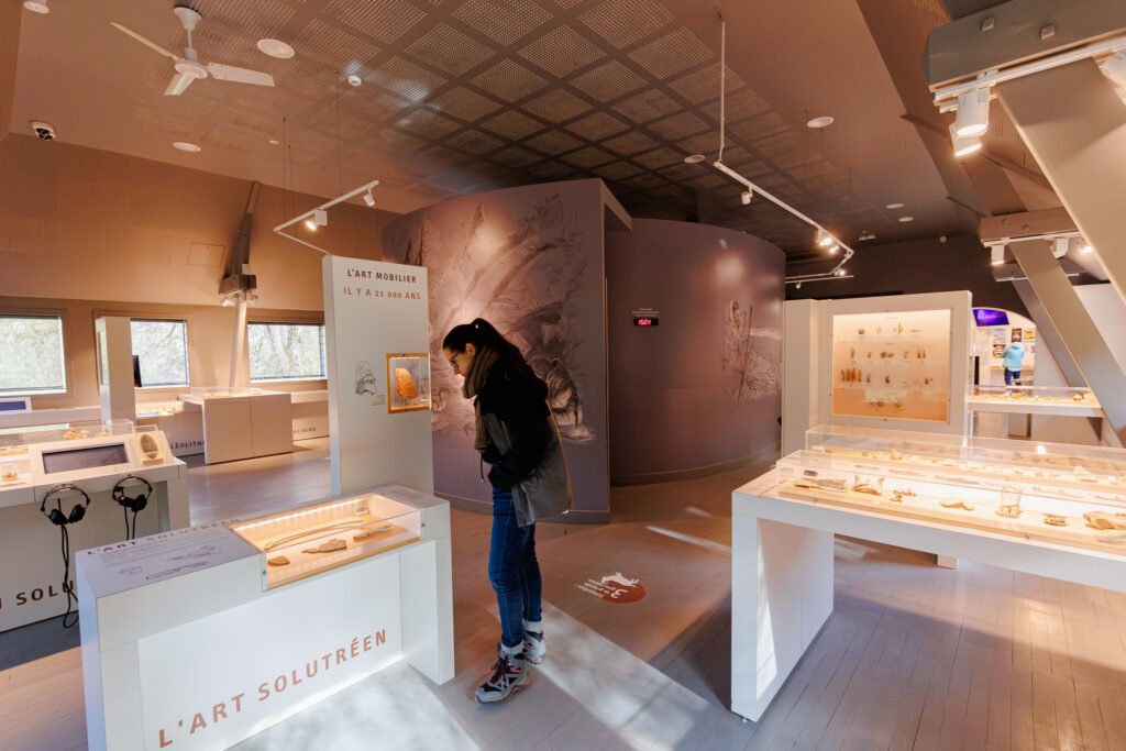 Visitor observing display cases of archaeological artifacts in the Saulges caves site museum.