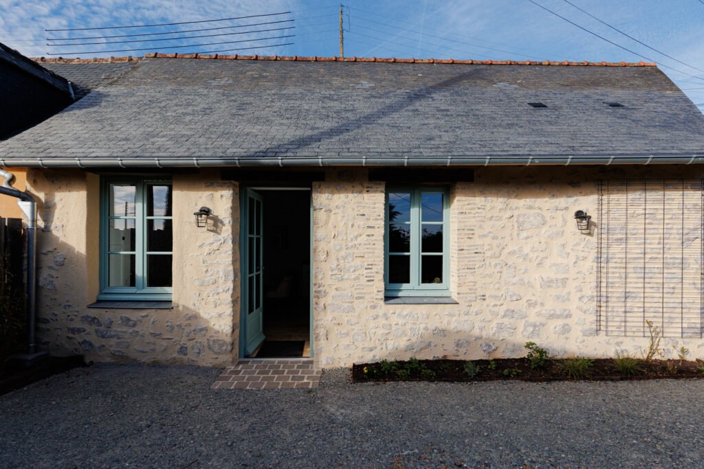 Stone facade of Le Logis du Pressoir vacation home in Sainte-Suzanne with the door slightly ajar.