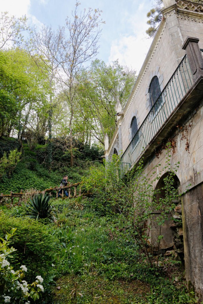 Visitor walking up the lush green stairway near the Saint-Cénéré oratory amidst luxuriant nature.