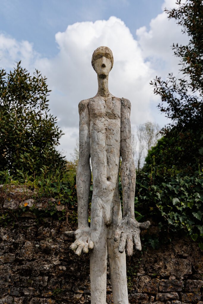 Stylized human sculpture with large hands in Saint-Pierre-sur-Erve.