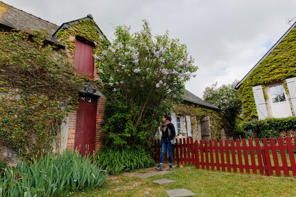 Tourist in front of an old flower-adorned stone house in Saint-Pierre-sur-Erve.