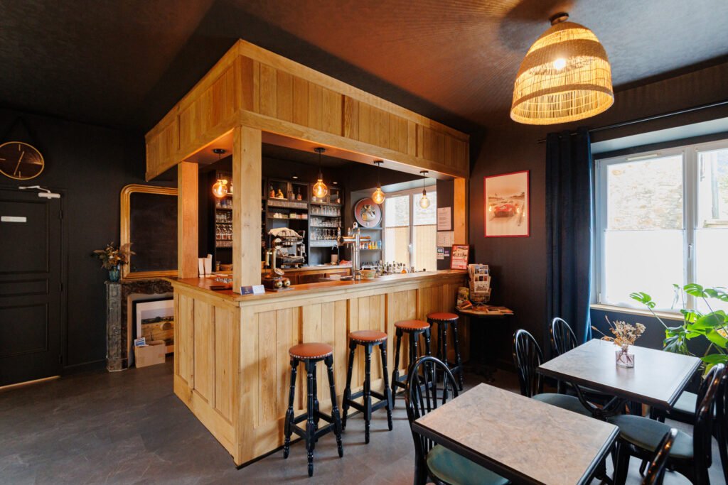 Interior of a cozy café with a large wooden counter, bar stools, and tables for customers.