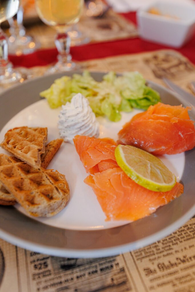 Plate of smoked salmon served with waffles, crème fraîche, and salad.