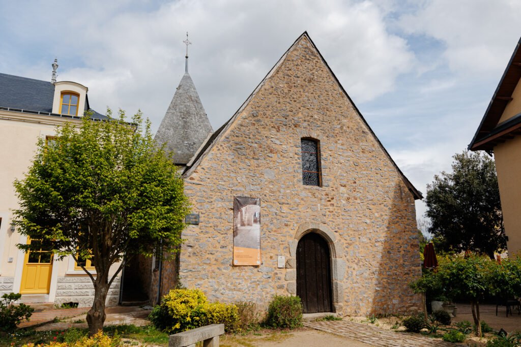 Facade of the medieval church of Saulges with its pointed bell tower and stone walls.
