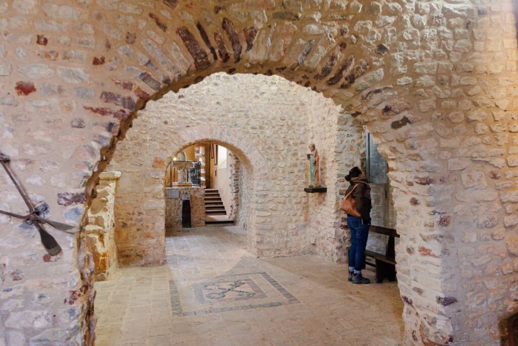 Interior visit of the medieval church of Saulges featuring stone walls and Romanesque arches.