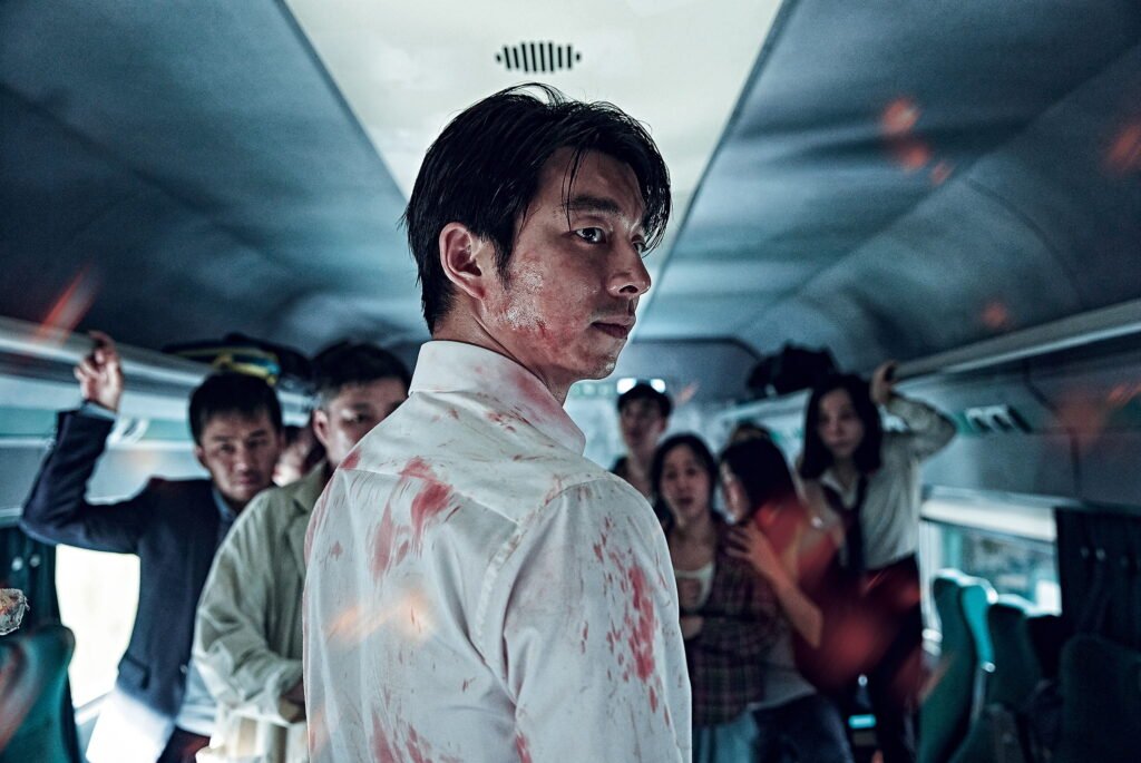 Homme ensanglanté dans le train du film Dernier train pour Busan avec d'autres passagers terrifiés.